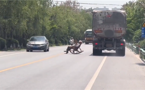 大爷马路中间手拿折扇躺摇椅上晒太阳 过往车辆纷纷减速避让