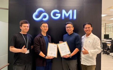 Four individuals pose in front of a GMI logo, holding signed documents as part of a collaboration announcement between Compal and GMI Cloud